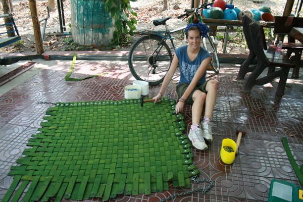 A woman sat on the floor next to a weaving project