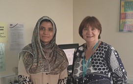 A further education learner and a teacher stand in front of a computer in a classroom